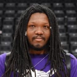 A photograph of Fletcher Sharpe looking into the camera wearing a dark purple jersey with some stadium seating shown in the background.